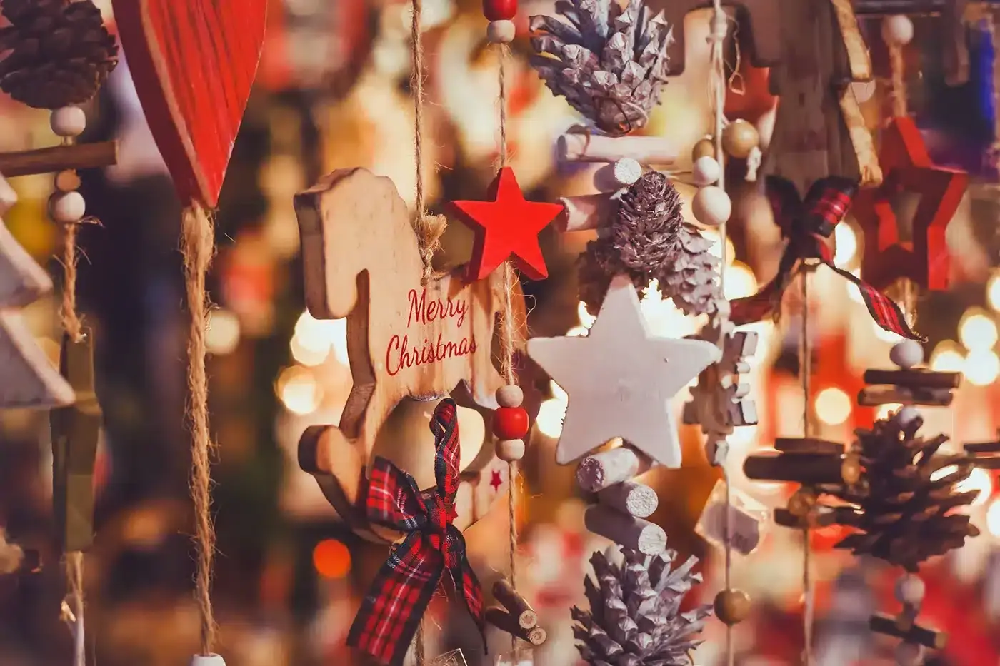 Close-up of hanging Christmas ornaments including stars, pinecones, and a wooden horse with 'Merry Christmas' written on it.