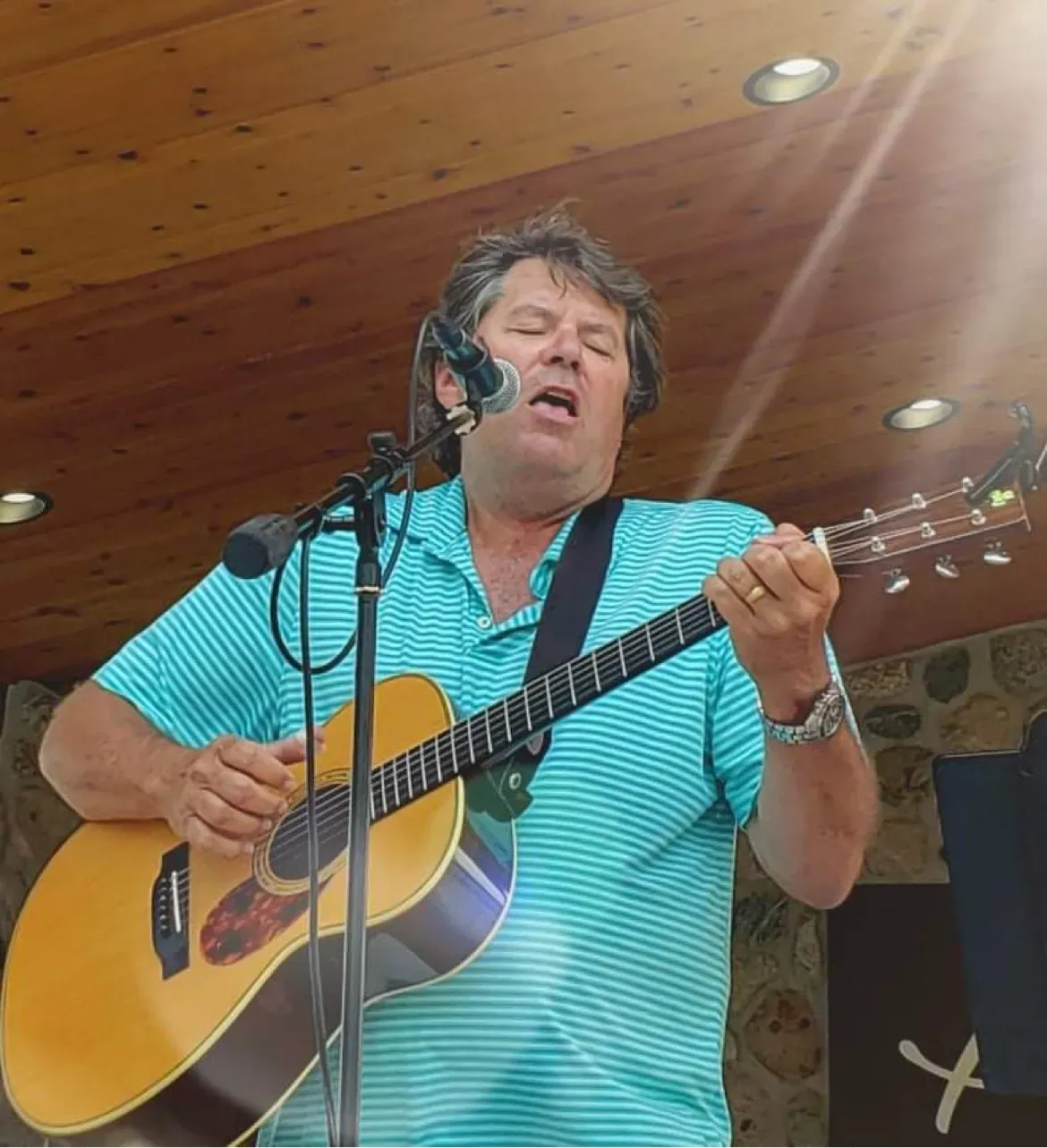 Paul Weidenbach singing and playing acoustic guitar indoors